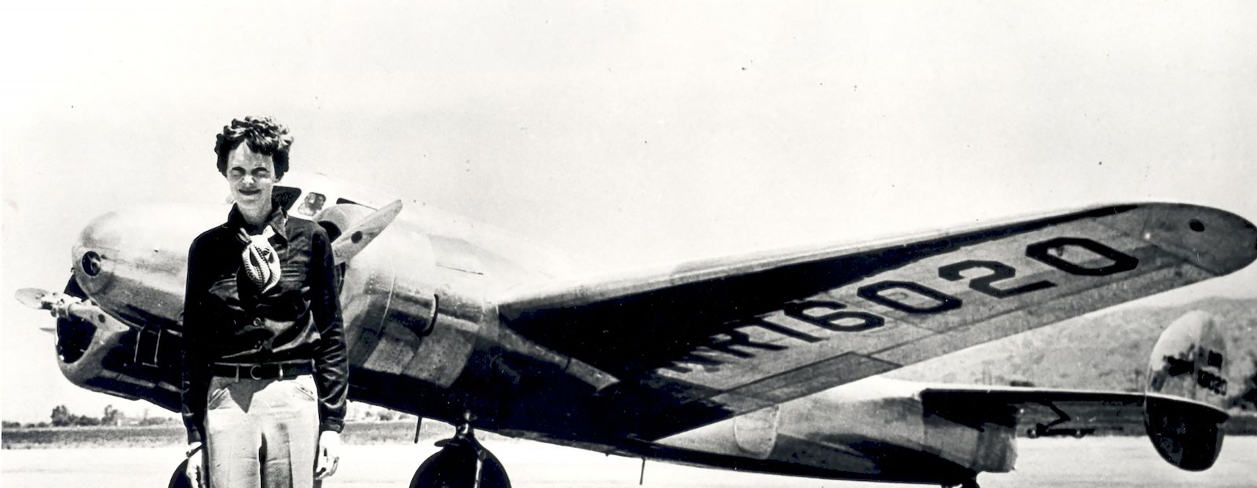 retro photo of a pilot standing beside an plane on a runway